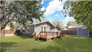 A single-story house with a wooden deck, a fenced yard, and a shed. - Spacious 4-bedroom house in welcoming San Antonio near trails, Pearl, Gardens (San Antonio)
