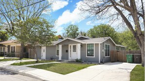A two-story residential building with a front porch, a small front yard, and a driveway. - Spacious 4-bedroom house in welcoming San Antonio near trails, Pearl, Gardens (San Antonio)
