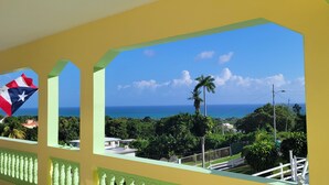 A view from a balcony with a clear sky, palm trees, and the ocean. - Loma Bella/ Private Villa for 14 near beach,2 homes  (Patillas)