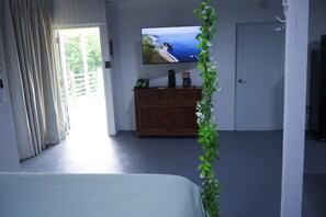 A room with a bed, a wooden dresser, a television displaying a scenic view, and a door. - Loma Bella/ Private Villa for 14 near beach,2 homes  (Patillas)