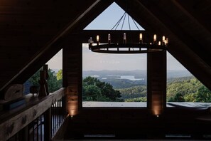 A room with a view of a lake and mountains, a wooden ceiling, and a chandelier. - Wellness Retreat: Epic Views·Gym·Sauna·Cold Plunge (Blue Ridge)