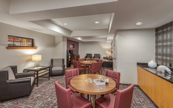 Une chambre d’hôtel comprenant un coin repas, un canapé, une télévision et un minibar.