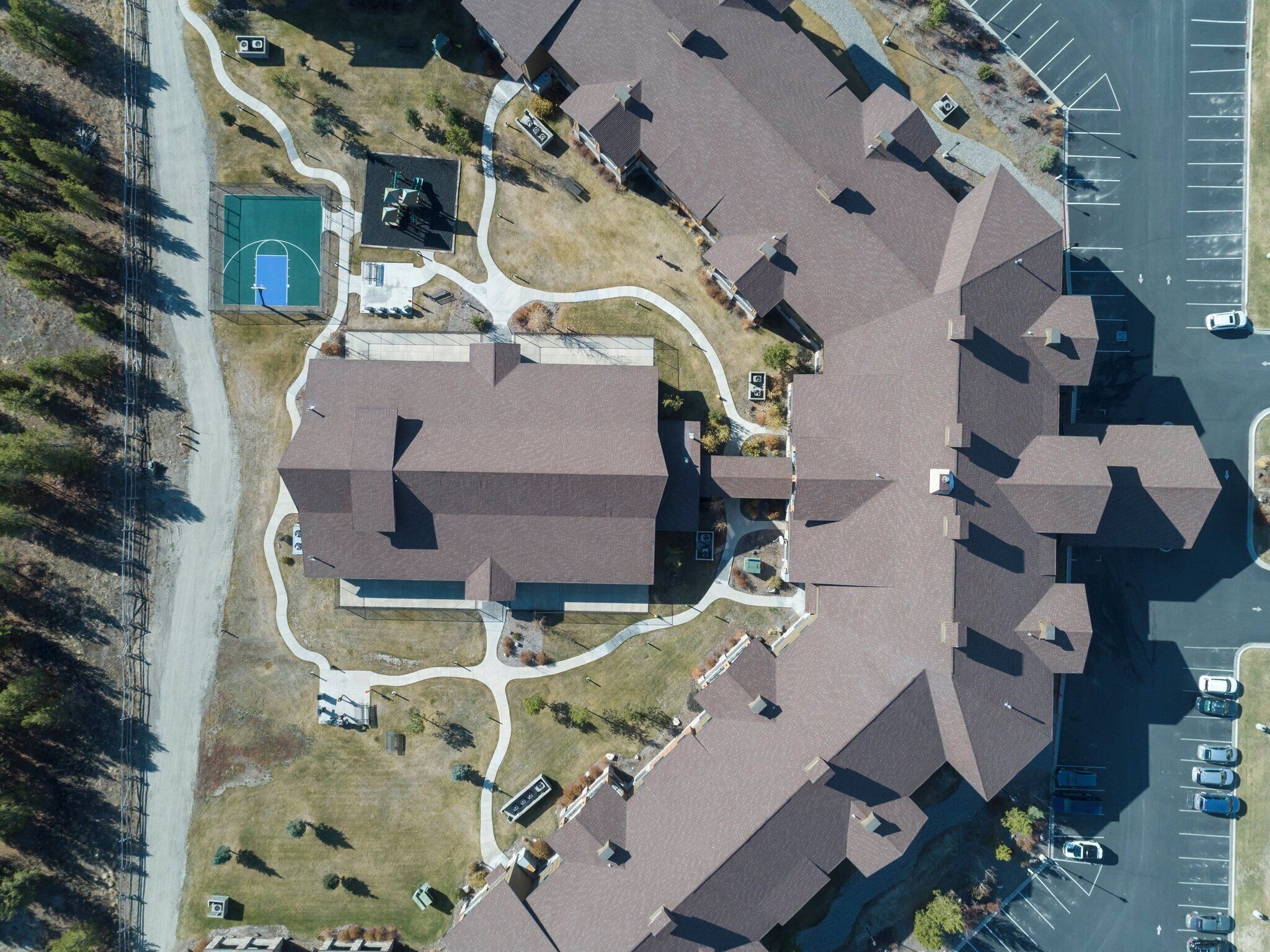 Vista aérea de una zona residencial con varias casas, una cancha de baloncesto y un estacionamiento.