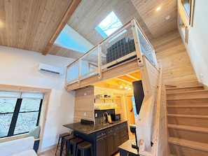 A loft-style room with a kitchen area, a dining table, and a window with a view.