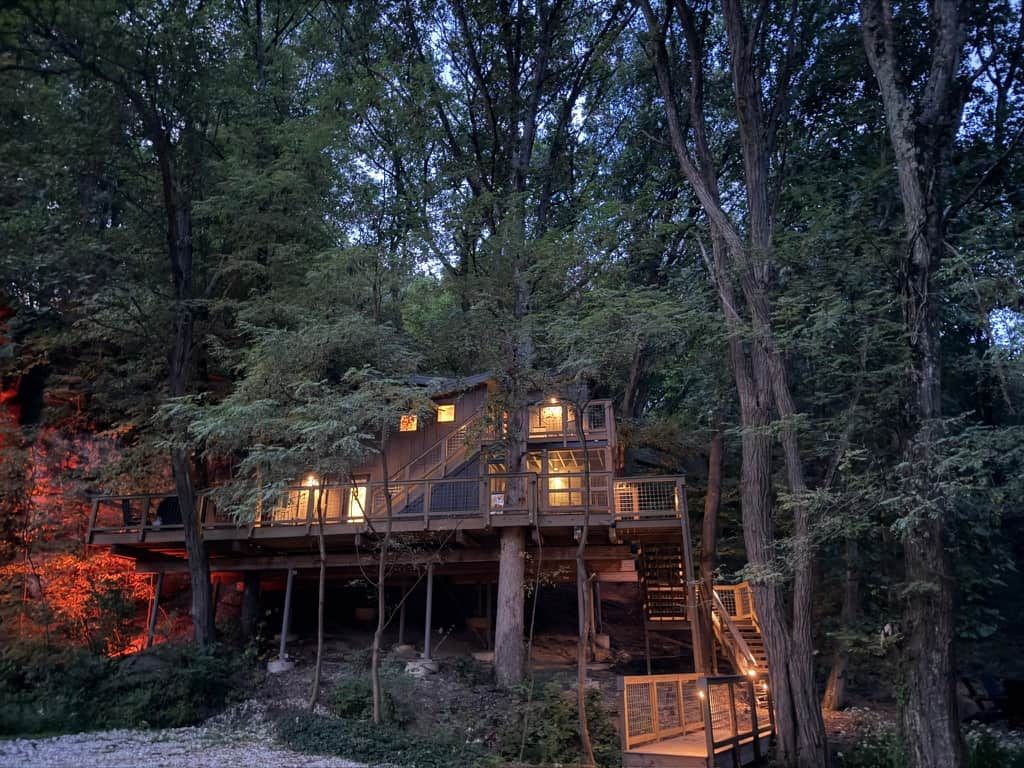 A multi-level wooden cabin with outdoor staircases, surrounded by trees.