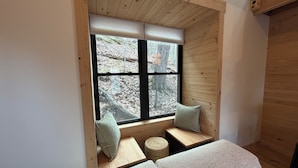 A cozy room with a built-in bench, a window with a view of trees, and a cushioned seating area.