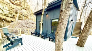A wooden deck with outdoor seating, a building with large windows, and a staircase.
