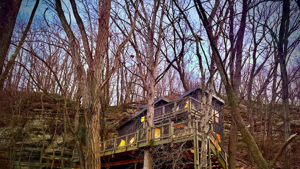 A treehouse with multiple levels, wooden railings, and a staircase.