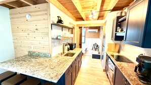 Une cuisine avec des poutres en bois, des plans de travail en granit et un îlot central doté de tabourets de bar.