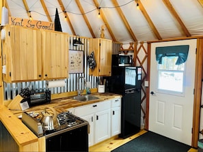 A compact kitchen with wooden cabinets, a gas stove, a microwave, and a refrigerator. - Luxury Yurt with private hot tub 15 min to Jay Peak Resort (Newport)