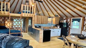 A cozy yurt with a loft bed, a kitchen area, and a dining space. - Luxury Yurt with private hot tub 15 min to Jay Peak Resort (Newport)