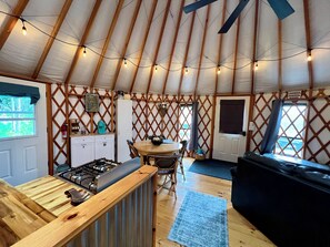 A cozy interior of a yurt with a kitchen area, dining space, and a seating area.