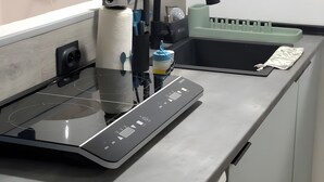 Eine Küche mit einer modernen Induktionskochplatte, einem Spülbecken und einer Arbeitsfläche mit verschiedenen Küchenutensilien.