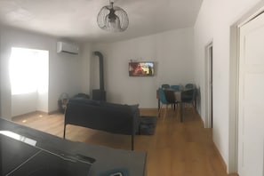 A living room with a sofa, a TV, a fireplace, and a dining area with chairs.