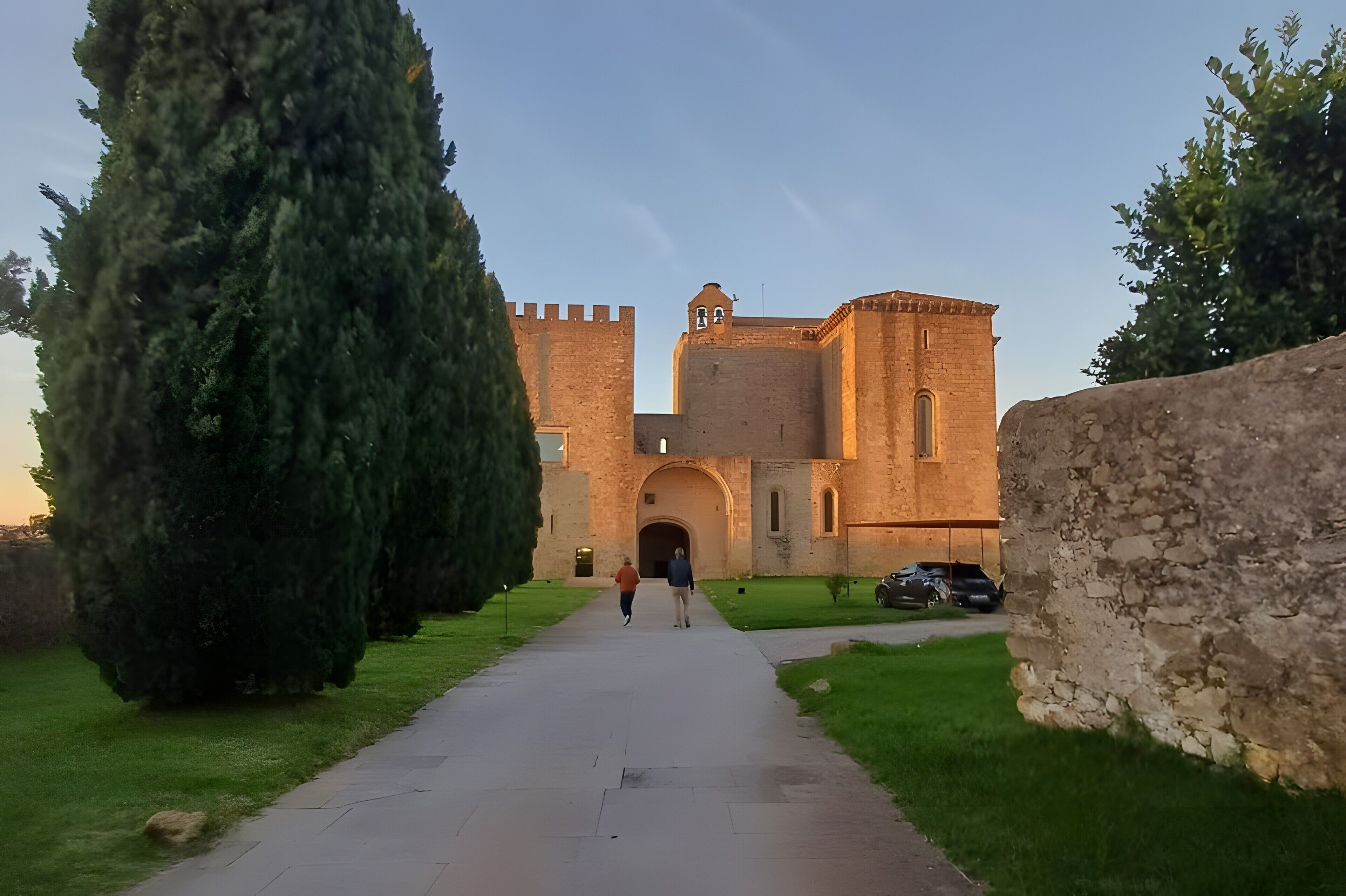 A pathway leading to a historic building with a prominent tower and arched entrance.