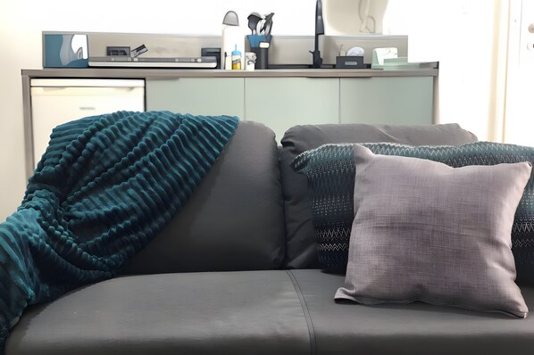 A modern living room with a sofa, pillows, and a blanket.