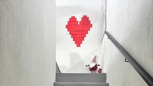 Eine Treppe, bestreut mit roten Rosenblättern, mit einer herzförmigen Dekoration am oberen Ende.