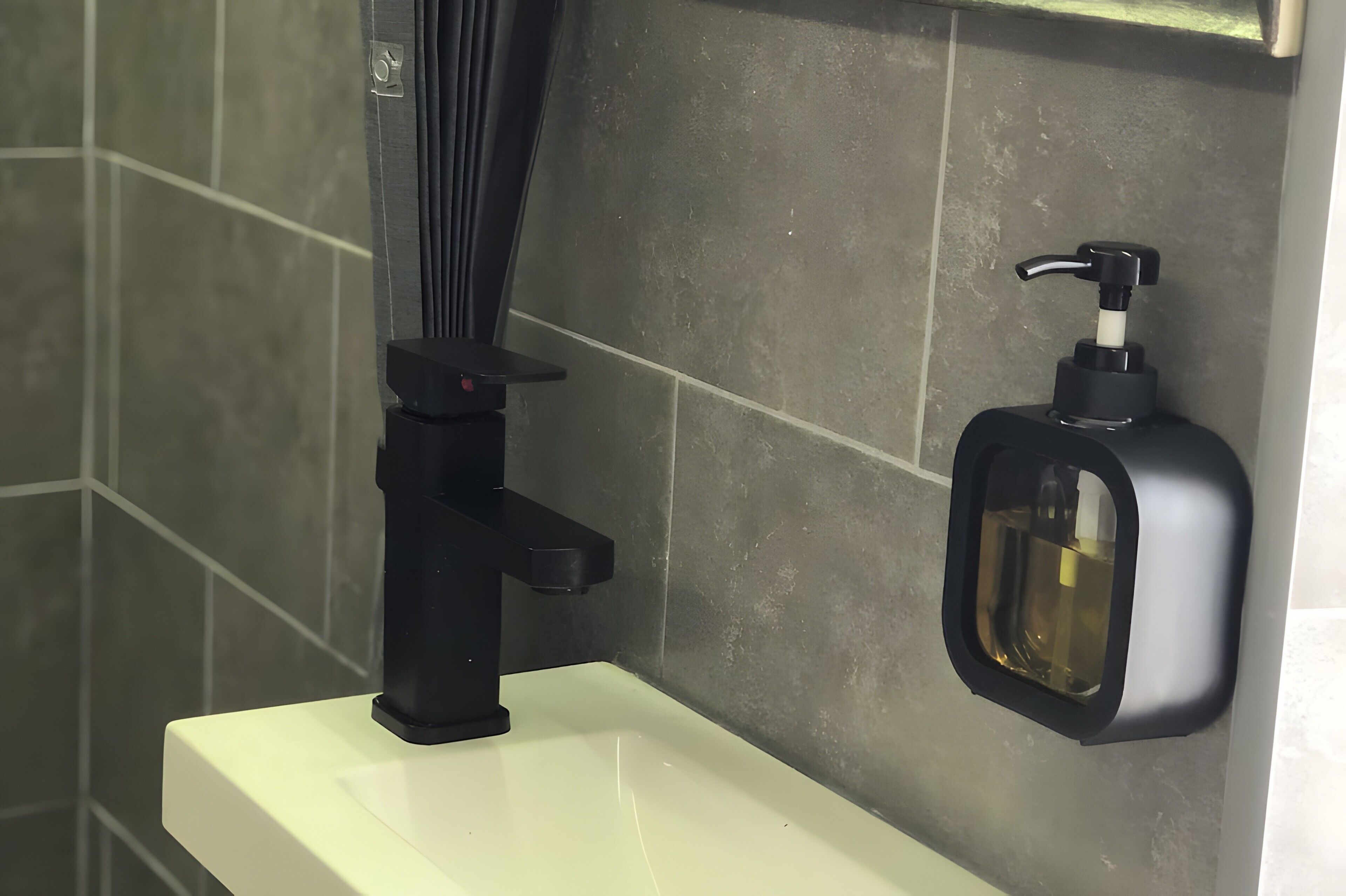 A bathroom with a white sink, a black faucet, and a soap dispenser mounted on the wall.