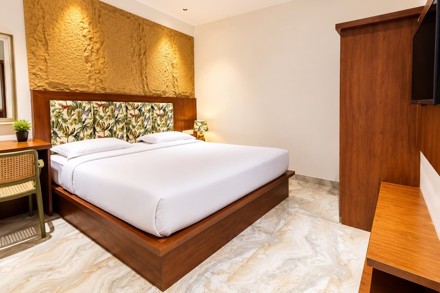 Habitación de hotel con una cama grande, cabecero de madera, un escritorio pequeño y un televisor.