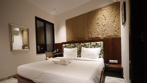 A neatly made bed with a wooden headboard, a bedside table with a phone, and a wall-mounted mirror. - Hotel Destin (Gwalior)