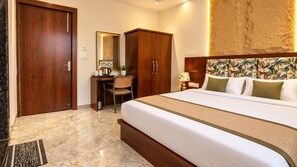 A hotel room with a bed, a desk, a chair, a wardrobe, and a large mirror. - Hotel Destin (Gwalior)