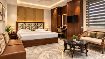 A hotel room with a large bed, a sofa, a desk, and a television.