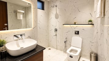 Un baño moderno con un lavamanos grande de color blanco, un inodoro y una ducha.