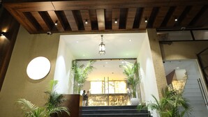 A hotel entrance with a wooden facade, a neon sign, and a staircase leading to the lobby. - Hotel Destin (Gwalior)