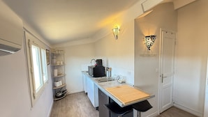 Una cucina compatta con un piano di lavoro in legno, una macchina da caffè e uno sgabello da bar.