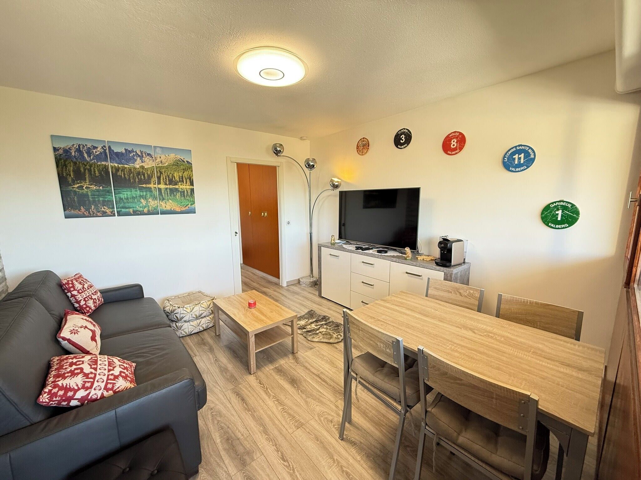 A compact living space with a sofa, a dining table, a TV, and a kitchen area.
