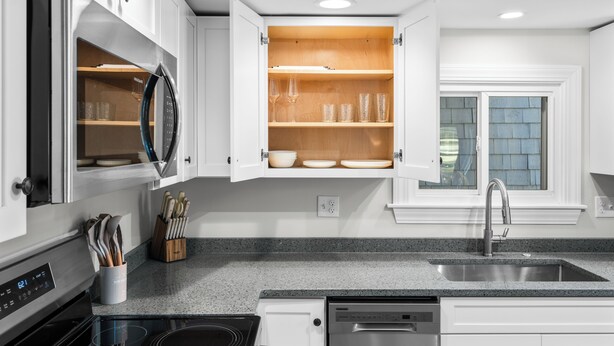 A modern kitchen with white cabinets, a granite countertop, a built-in oven, and a stainless steel sink. - The Essex of Gloucester (Gloucester)