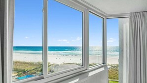 Ein Zimmer mit großen Fenstern und Blick auf einen Strand.