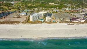 Luftaufnahme eines Küstenresorts mit einem großen Hotel, einem Strand und umgebender Vegetation.