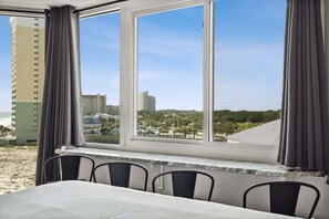 A hotel room with a large window offering a view of the beach and cityscape. - Top Of The Gulf 704 - Beautiful Studio (Panama City Beach)