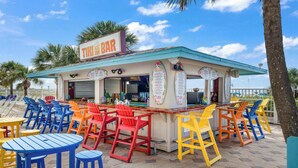 Un bar tiki con posti a sedere all'aperto e una bacheca dei prezzi.
