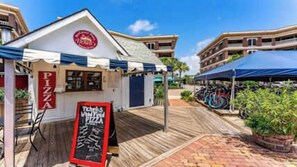 Un restaurant en bord de mer avec une terrasse en bois, un menu écrit à la craie et un vélo garé à proximité.