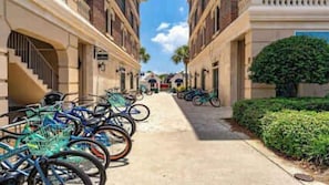 Une rangée de vélos est stationnée le long d’un trottoir dans un quartier résidentiel, de part et d’autre duquel se trouvent des immeubles.