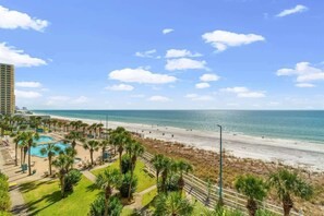 Ein Hotel direkt am Strand mit Schwimmbad, Palmen und Blick auf den Strand.