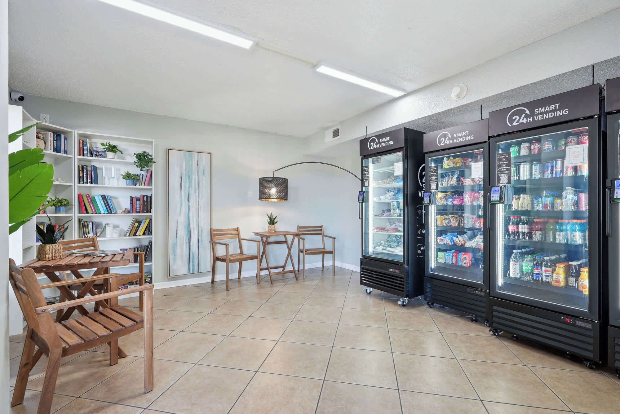 Un intérieur moderne comprenant un coin salon, une bibliothèque et deux distributeurs automatiques ouverts 24 heures sur 24.