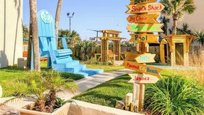 Een resort met een zwembad, strand en diverse voorzieningen, zoals een snackbar, een grote ligstoel en borden die naar Jamaica wijzen.