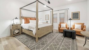 A bedroom with a four-poster bed, a ceiling fan, a nightstand, a desk, two chairs, and a patterned rug. - Village of SoWal B257 (Seacrest)