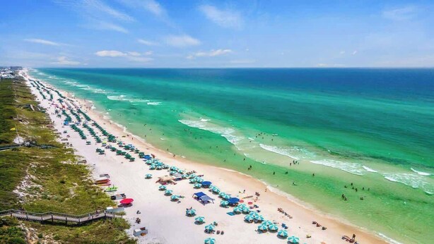A beach with rows of umbrellas and sun loungers, a walkway, and the ocean. - Village of SoWal B257 (Seacrest)