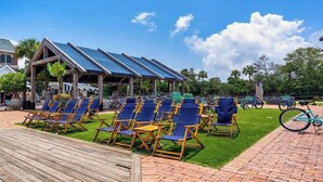 A covered outdoor seating area with blue chairs and solar panels on the roof. - Village of SoWal B257 (Seacrest)