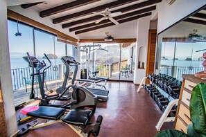 Un gimnasio con equipamiento de ejercicio y vista al mar.