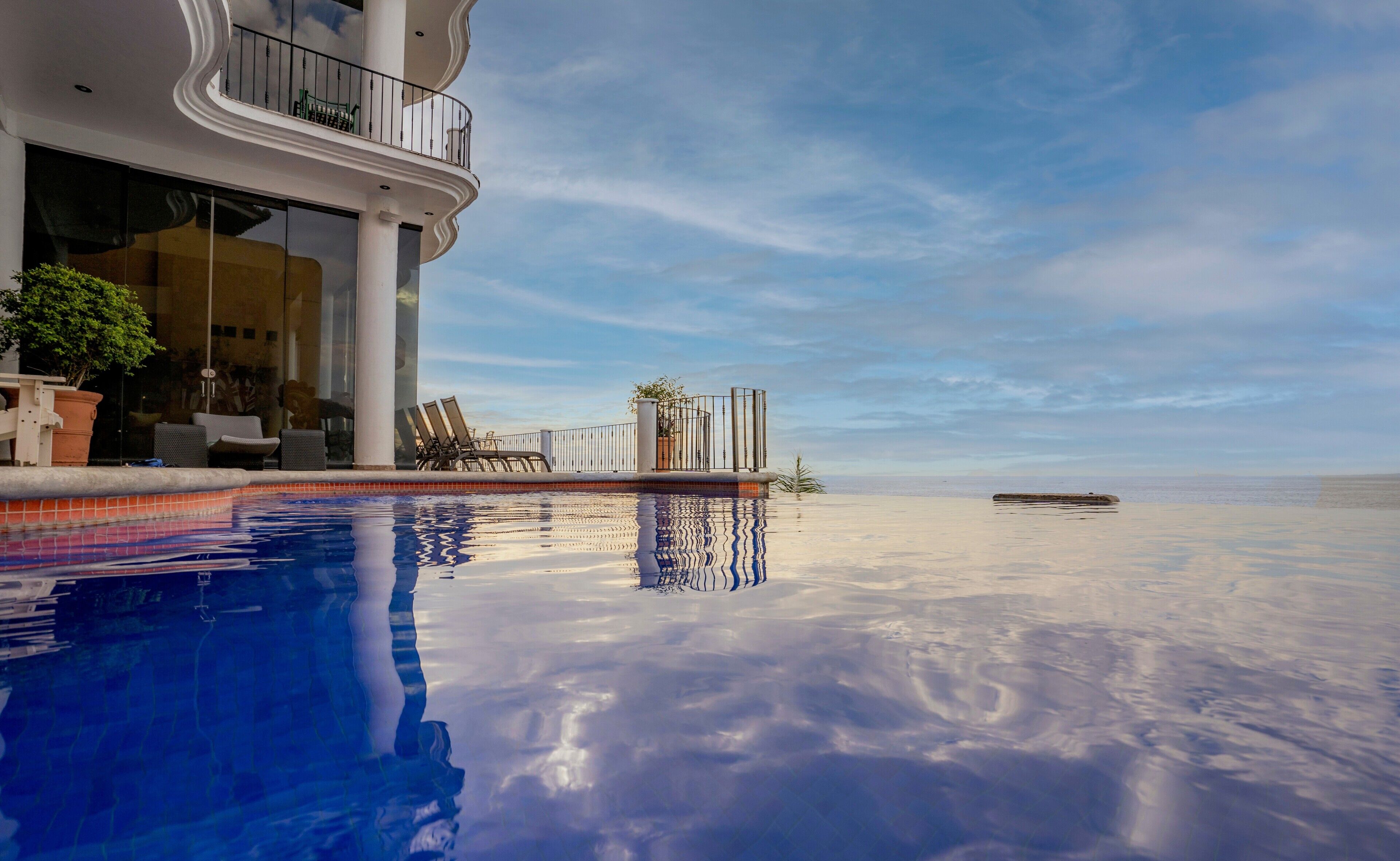 Un hotel moderno con piscina, sillas de descanso y vistas al océano.