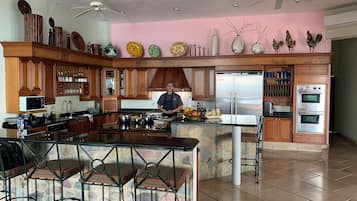 Una cocina moderna con armarios de madera, una isla central y una pared de acento rosa.