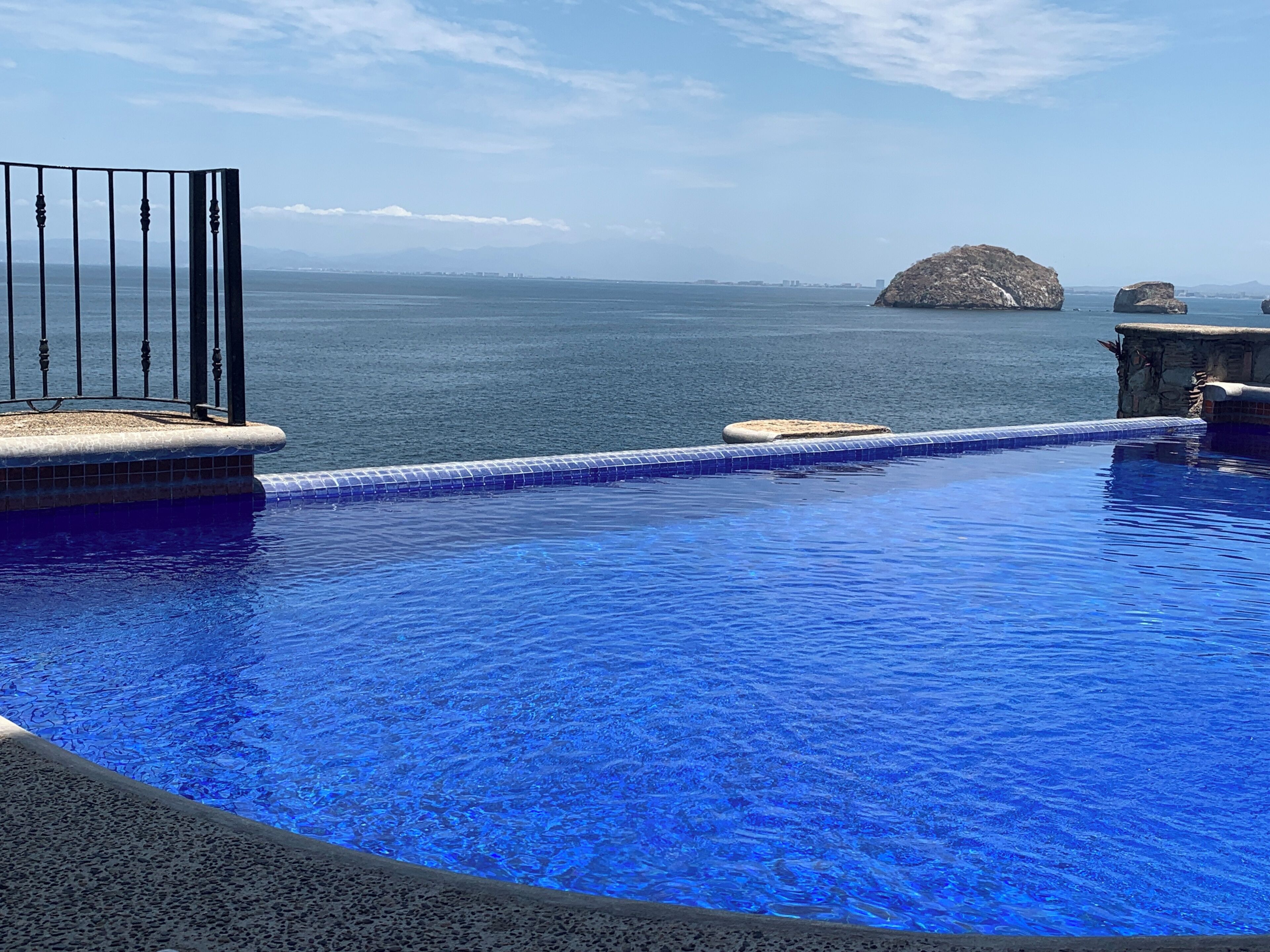 Una piscina con vistas al mar y montañas al fondo.