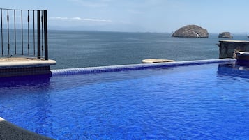 Una piscina con vistas al mar y montañas al fondo.