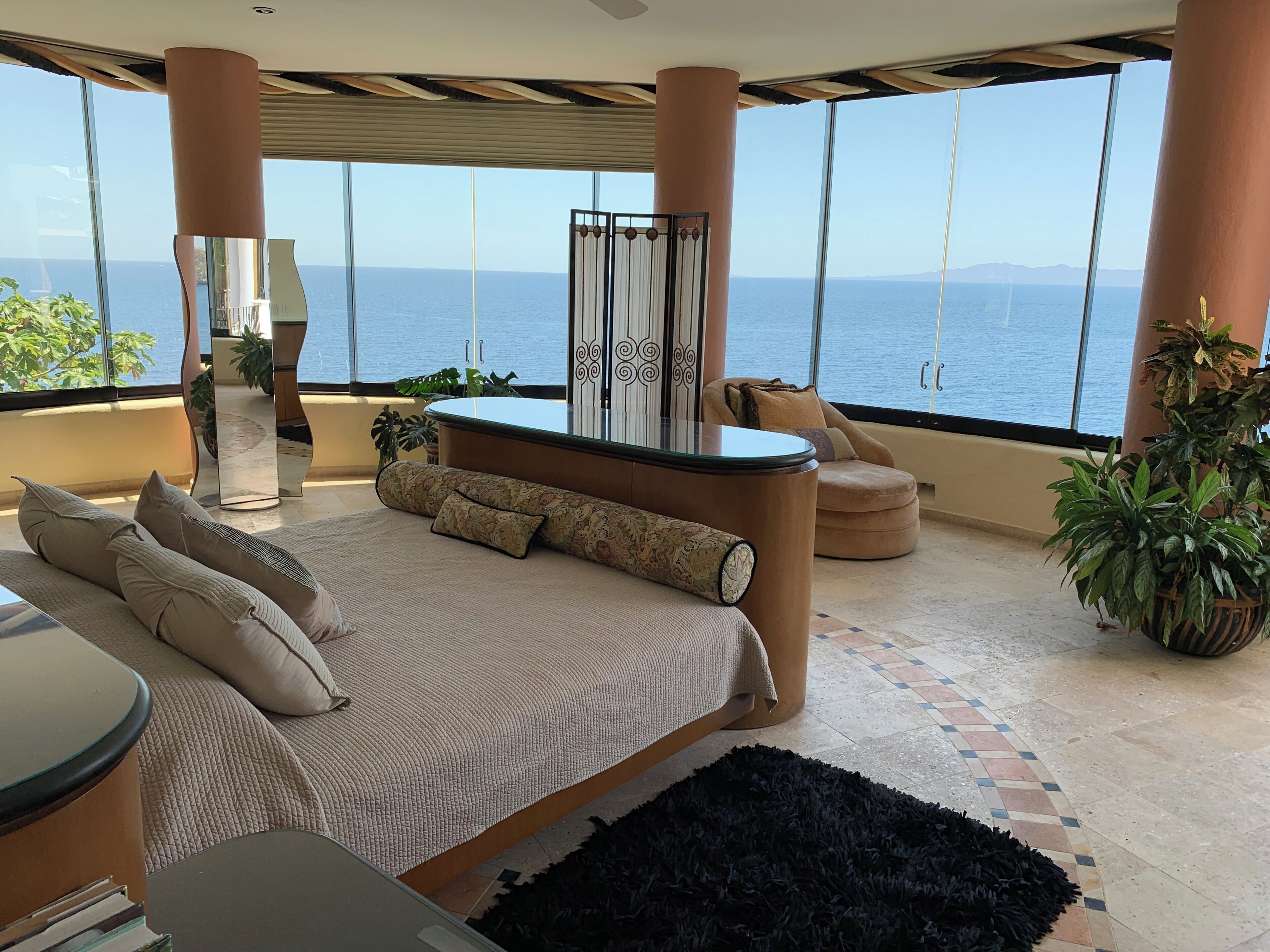 Een slaapkamer met een groot bed, een zithoek en uitzicht op zee.