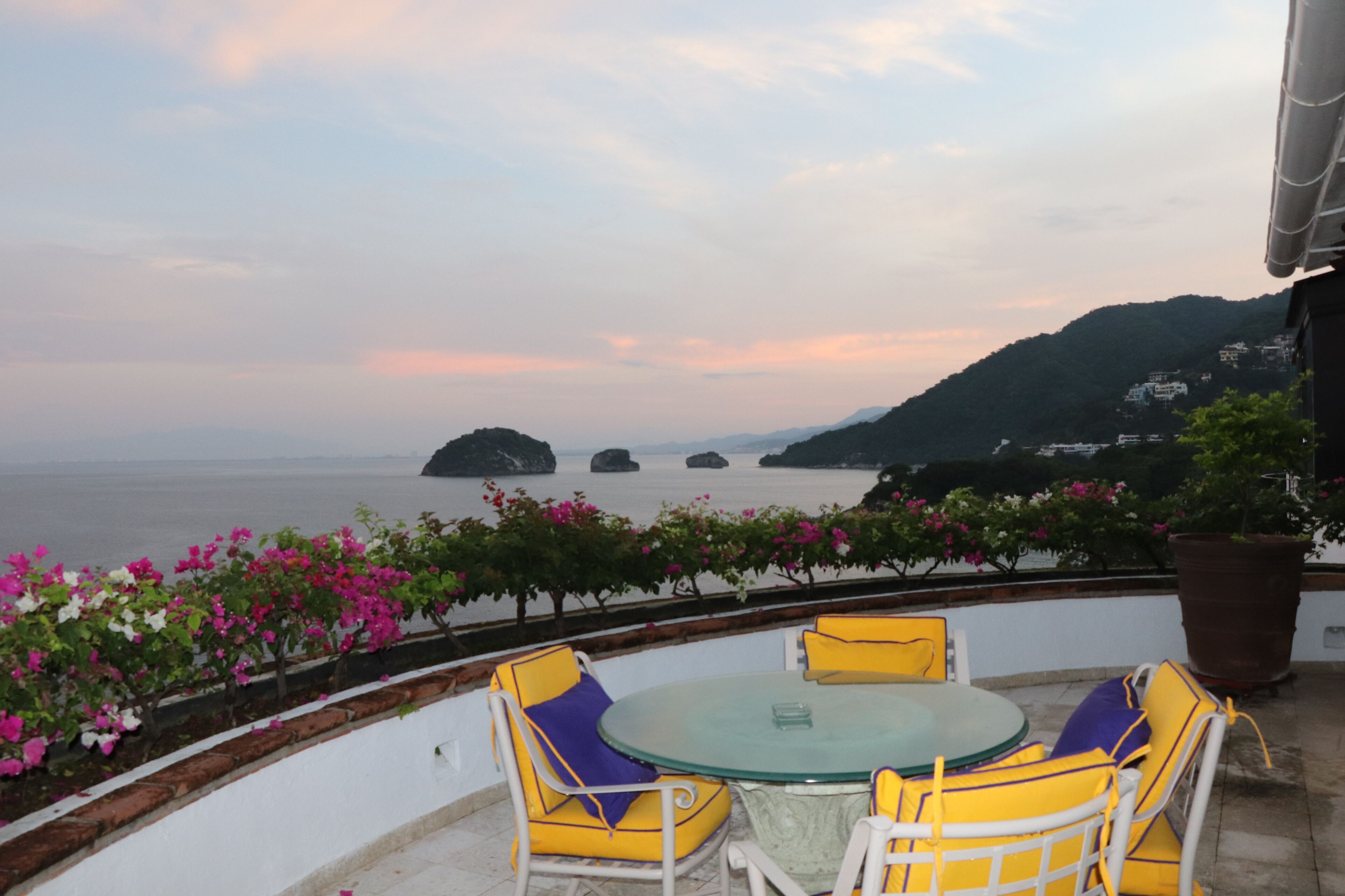 Una terraza con una mesa y sillas, con vista a un cuerpo de agua y islas distantes.